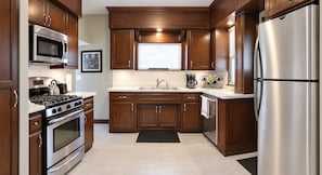 Une cuisine moderne dotée d’appareils électroménagers en acier inoxydable, de meubles en bois et d’un plan de travail noir.
