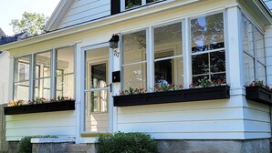 Una casa con porche cubierto, ventanas amplias y jardineras florales.