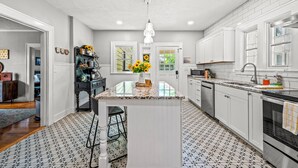 Una cocina moderna con armarios blancos, encimera de granito y una isla central.