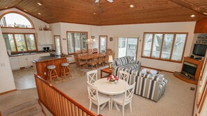 A spacious living area with a dining table, striped sofa, and wooden ceiling. - PLEASURE ISLAND - 5 BR Home in Schooner Ridge w/Access to Community Pools & Rec Center (Duck)