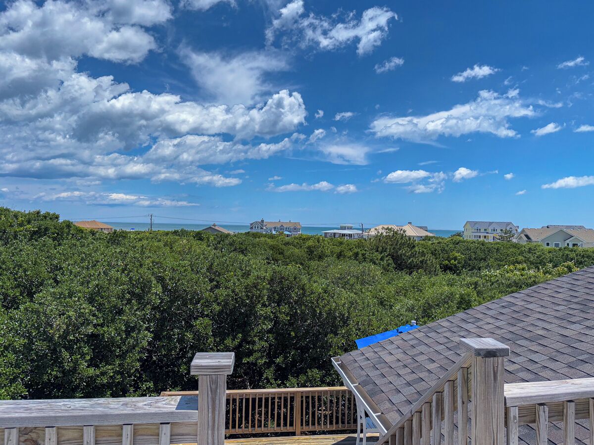 A view from a balcony overlooking a lush green landscape with a clear blue sky.