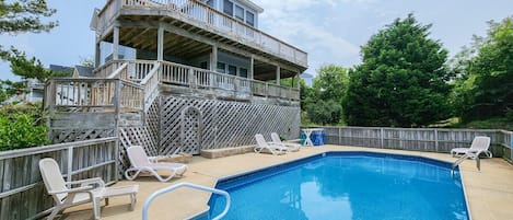 A swimming pool with lounge chairs and a wooden deck.