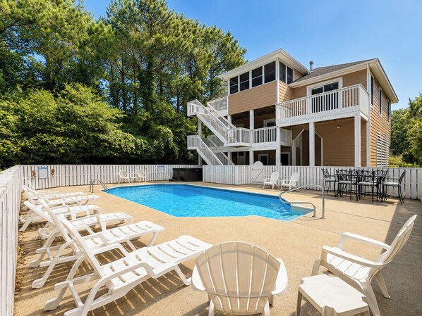 A pool area with lounge chairs and a building with a balcony.