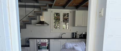 A modern kitchen with white cabinets, a built-in oven, and a wooden ceiling.
