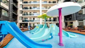 Uma área de parque aquático com várias escorregas e uma piscina.