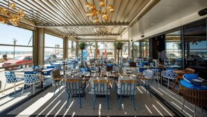 Restaurante com área externa, janelas amplas e design moderno no teto.