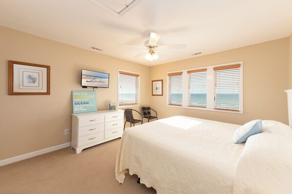 A bedroom with a bed, a dresser, a television, and a ceiling fan.