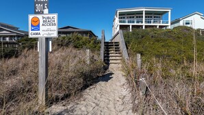 A public beach access sign with a beach path leading to a house.