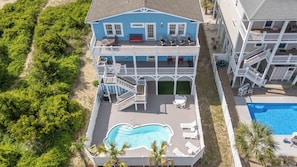 A two-story house with a swimming pool, a deck, and a view of the beach.