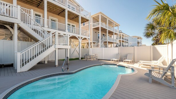 A pool area with a wooden deck, white railings, and multiple levels of balconies.