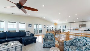 A spacious living area with a blue sofa, patterned armchairs, and a ceiling fan.