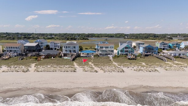 Propiedad frente a la playa con varias casas, una bandera y una playa de arena.