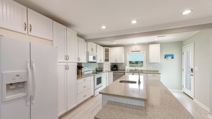 Una cocina moderna con armarios blancos, encimera de granito y horno empotrado.