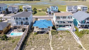 Zona residencial costera con varias casas, una piscina y un camino de acceso a la playa.