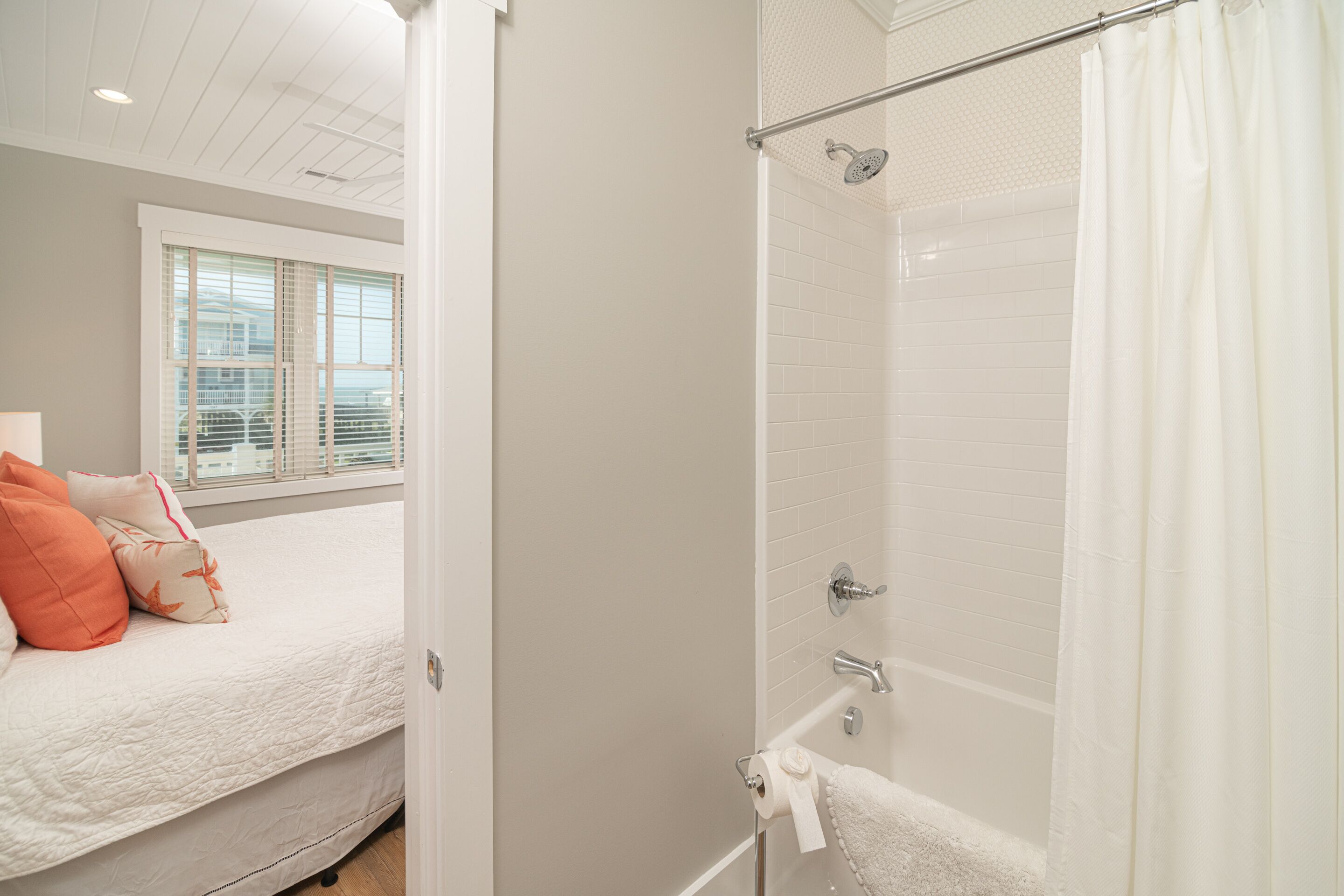 A bedroom with a bed, a window, and a shower area.