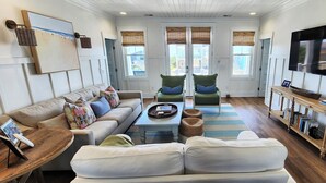 A living room with a sofa, armchairs, a coffee table, and a TV. - Hobbs Realty - Spend many an “Oh Happy Day” when you enjoy this charming home with a pool. (Holden Beach)