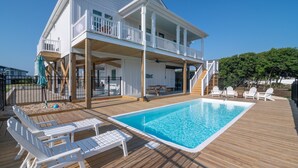 A two-story house with a wooden deck and a swimming pool. - Hobbs Realty - Spend many an “Oh Happy Day” when you enjoy this charming home with a pool. (Holden Beach)