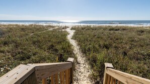 A wooden boardwalk leading to a beach with a clear sky. - See why this is “Our Happy Place” in this pet-friendly, oceanfront home with a hot tub. (Holden Beach)