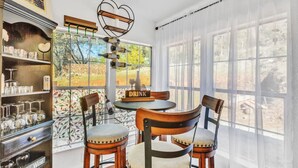 Uma sala de jantar com uma mesa redonda, quatro cadeiras de madeira, um espaço para vinhos e um letreiro com a palavra 'DRINK'.