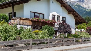Una casa di montagna con un balcone in legno, una recinzione di legno e vista sulle montagne.