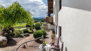Un balcone con vista su un giardino, un tavolo e due sedie.
