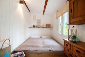 Ein Zimmer mit Bett, Holzkommode und Fenster.