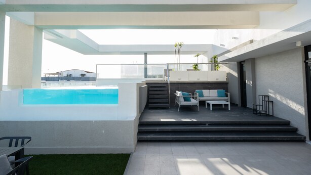 Et moderne udeområde med swimmingpool, siddepladser og en trappe til en etage over.