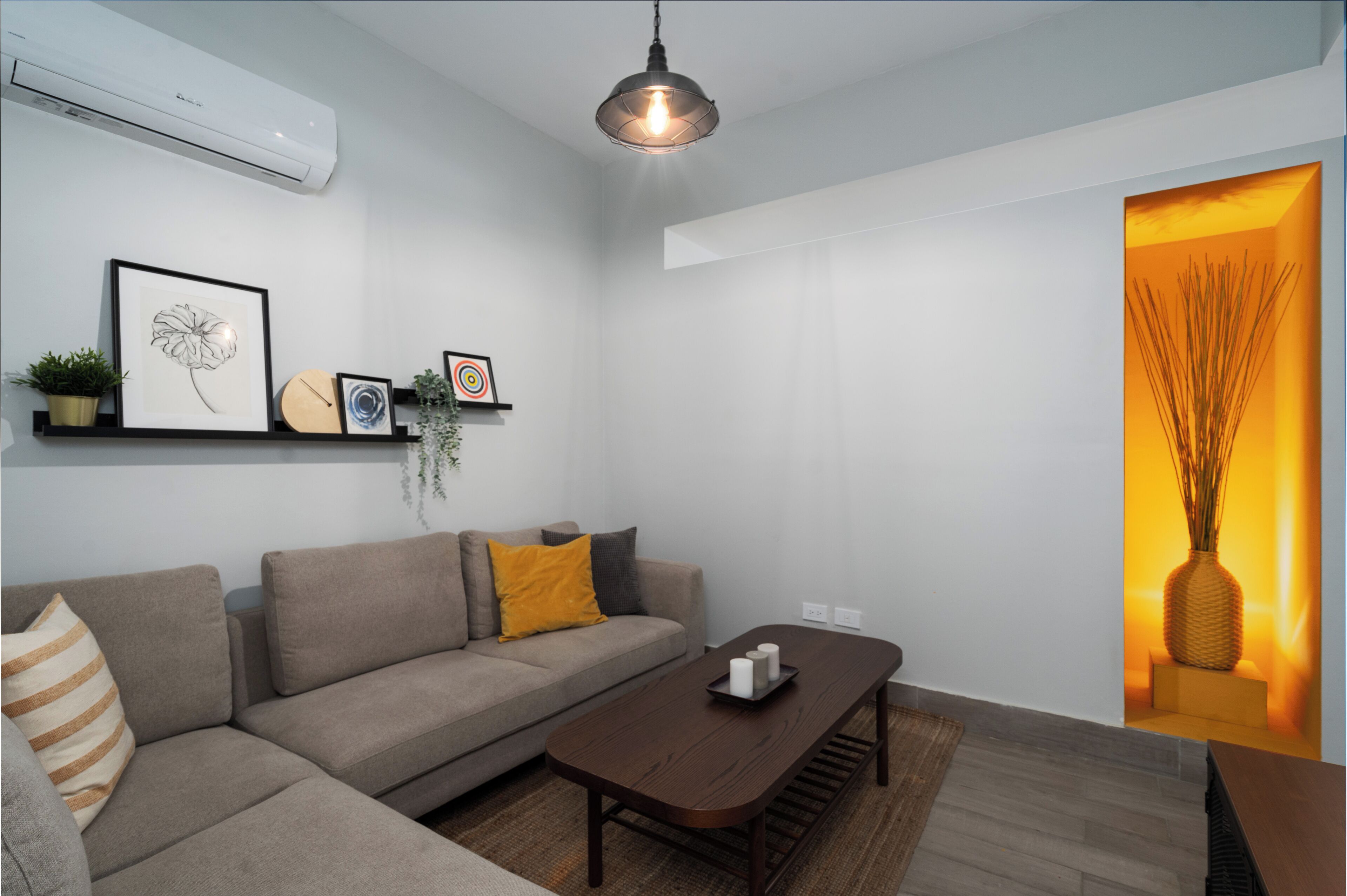 A modern living room with a sofa, a coffee table, and a hanging light fixture.