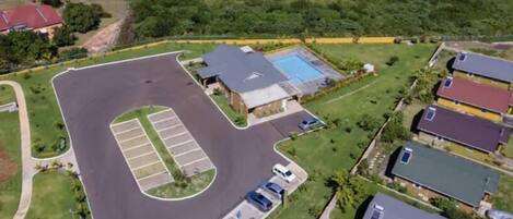 Vista aérea de una zona residencial con un estacionamiento amplio, una piscina y varias casas.