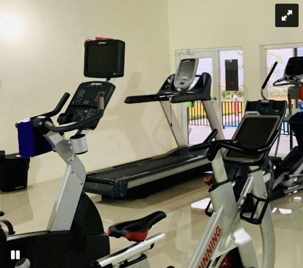 Un gimnasio con bicicletas estáticas, cinta de correr y máquina de remo.