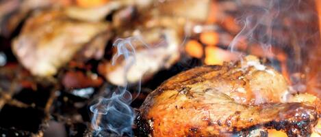 A close-up of a grill with meat cooking over flames.