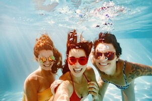 Tre persone sott'acqua in piscina.