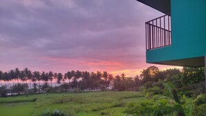 A view of a lush green field with a balcony overlooking a sunset. - Rocas De Amancio Private Beachfront Estate (Puntarenas Province)