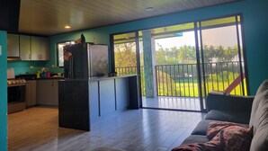 A modern kitchen with a refrigerator, stove, and cabinets. There is a balcony with a view of greenery. - Rocas De Amancio Private Beachfront Estate (Puntarenas Province)