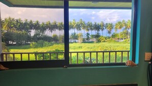 A kitchen with a double sink and a window overlooking a lush green landscape with palm trees. - Rocas De Amancio Private Beachfront Estate (Puntarenas Province)