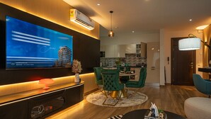 Een moderne woonkamer met een flatscreen televisie, groene beklede fauteuils, een ronde salontafel en een vloerkleed met een zebraprint.
