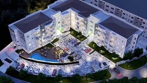 Een modern meerlaags hotel met een centrale binnenplaats, buitenzwembad en parkeerplaats.