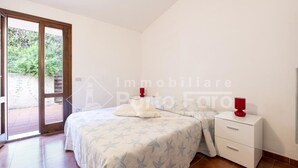 Ein Schlafzimmer mit einem Bett, einem Nachttisch und einer Schiebetür zu einem Außenbereich.