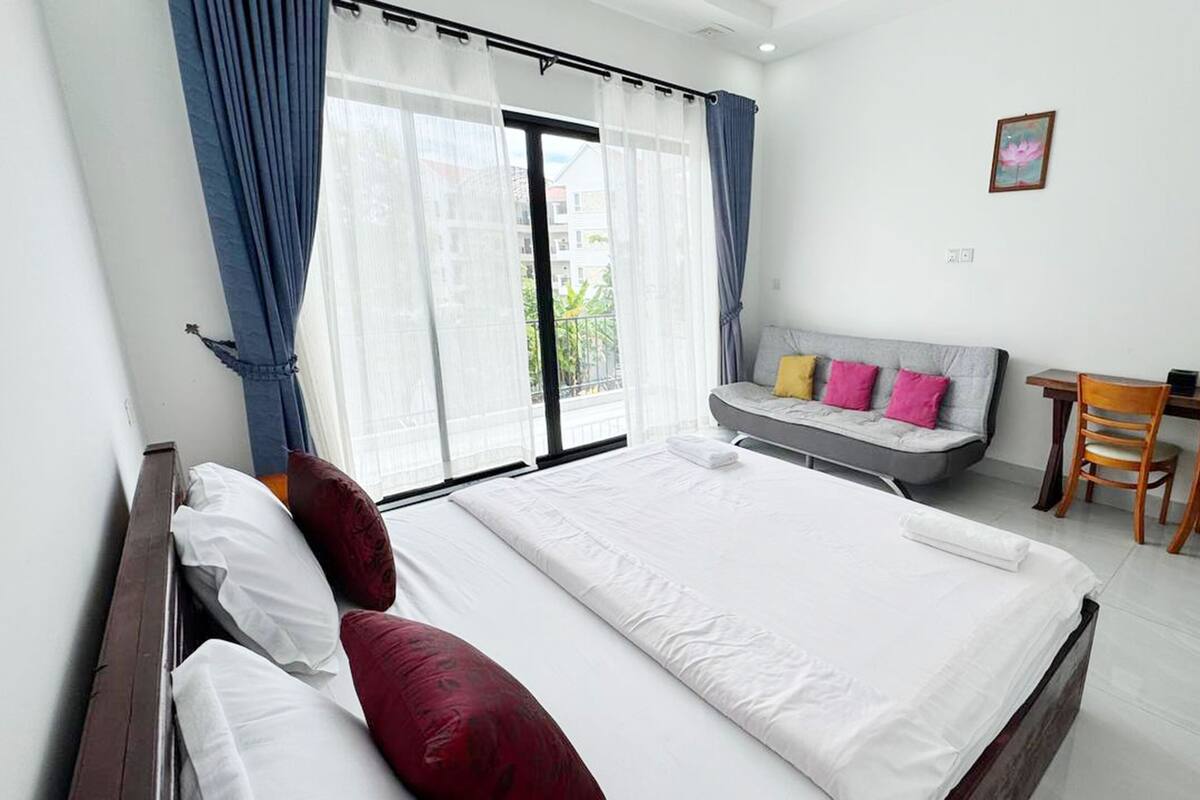 A hotel room with a large bed, a sofa, a desk, and a chair.