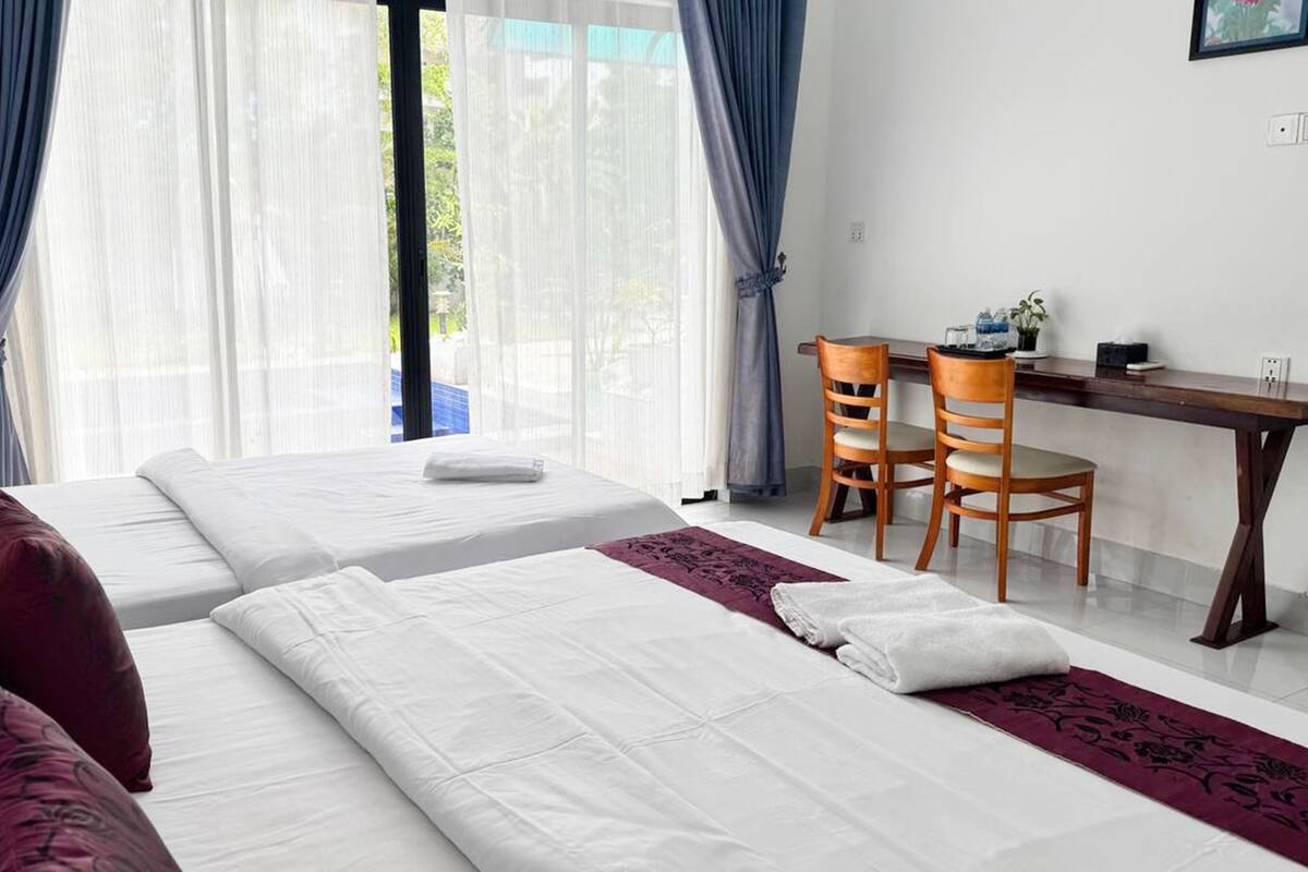A hotel room with two beds, a desk, and chairs.