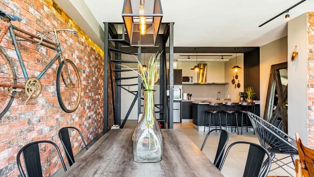 A dining area with a wooden table, chairs, a vase with plants, a brick wall, and a bicycle. - Most amazing view of Mexico City. Pool + gym + parking + AC (Ciudad de México)