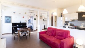 A modern living space with a dining area, a red sofa, and a kitchen with white cabinets. - Casa del Maestro Apartment (Milano)