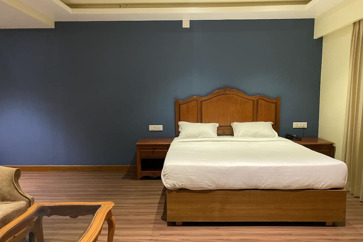 Ein Hotelzimmer mit einem großen Bett, einem Holzkopfende, Nachttischen und einem Holzstuhl.
