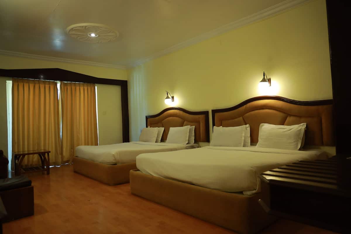 Ein Hotelzimmer mit zwei Betten, Holzboden und einer Decke mit einer dekorativen Leuchte.