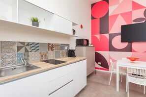 A modern kitchen with a sink, microwave, and a dining area with a table and chairs. - Taormina Center Suite Apartment with In-Room Jacuzzi (Taormina)