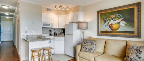 A compact living space with a kitchenette, a sofa set, and a dining area.