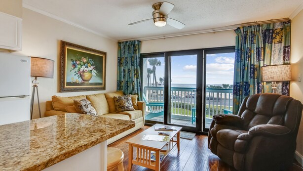 A living room with a sofa, a recliner, a coffee table, and a painting on the wall. - Casa Del Mar by Ryson Vacation Rentals (Galveston)