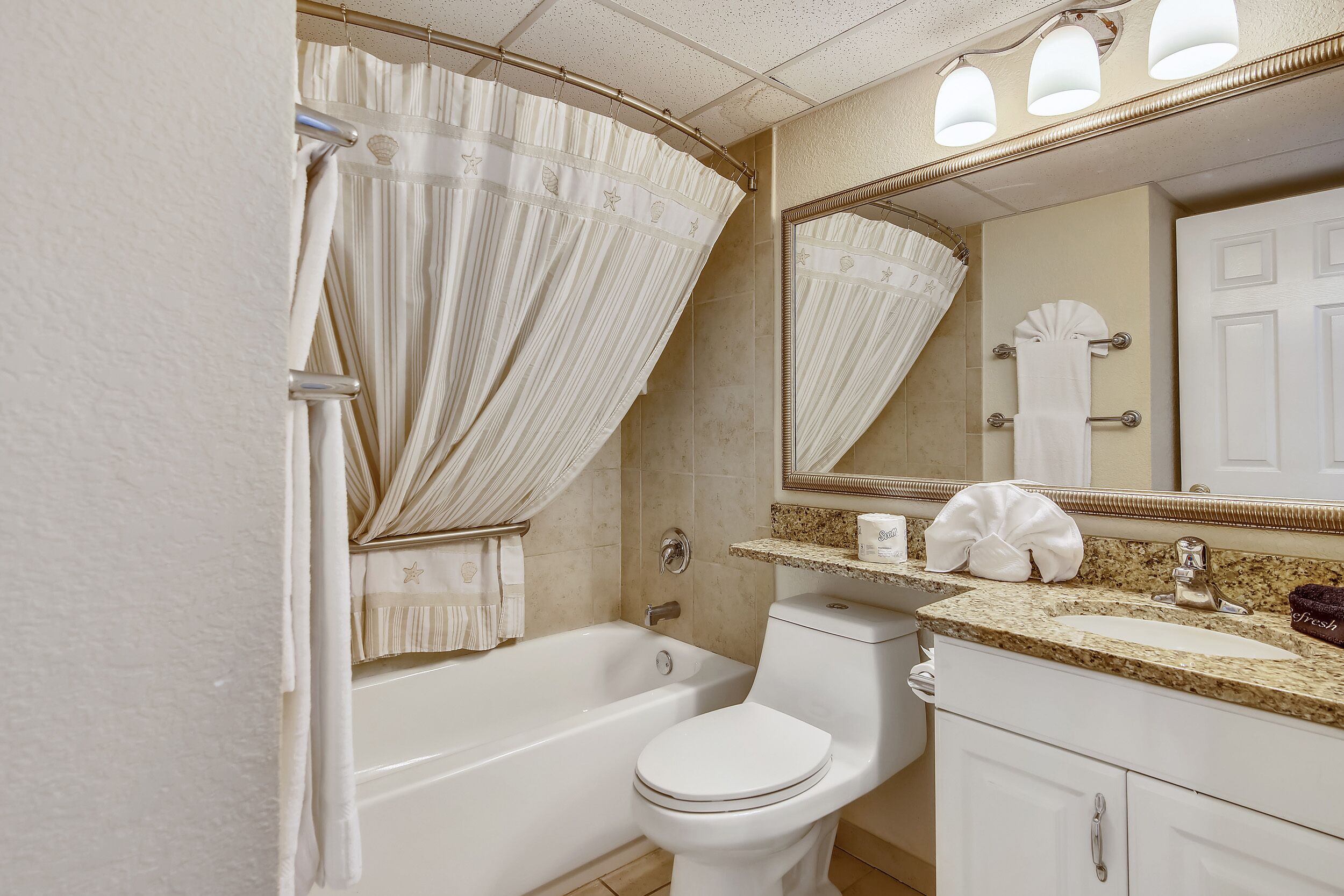 Un baño con bañera, inodoro y tocador con espejo.