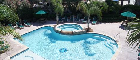 A swimming pool with multiple levels of seating and palm trees.