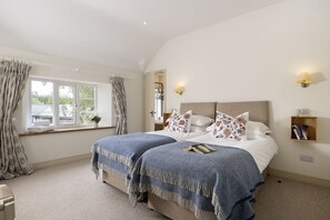 A bedroom with a bed, two bedside tables, a window with curtains, and a wall-mounted lamp.